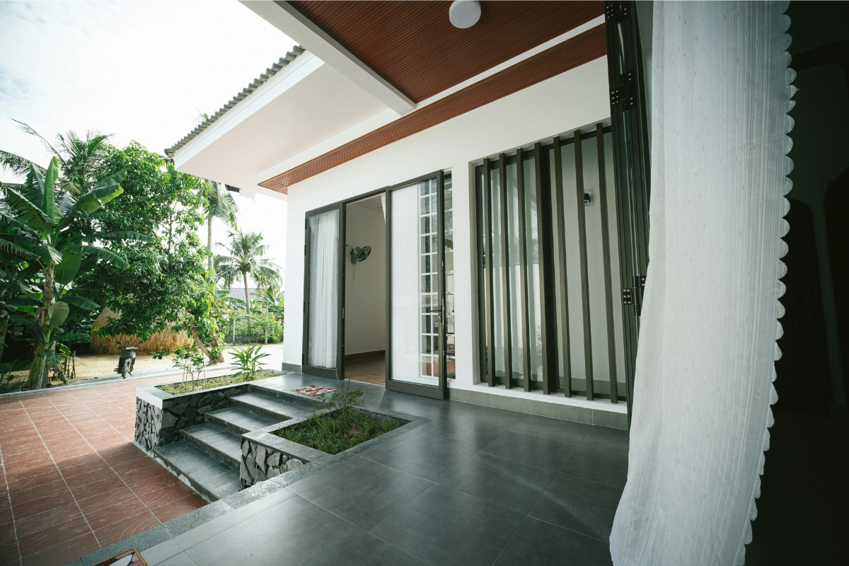 Zero threshold flush door threshold indoor outdoor with continuous large format tile flooring flowing seamlessly from living room to patio