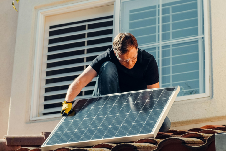 Solar battery storage home cost comparison showing a Tesla Powerwall installed on a residential garage wall alongside rooftop solar panels